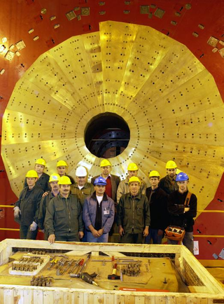 Russian scientists standing in front of the brass endcap at CERN’s CMS experiment.